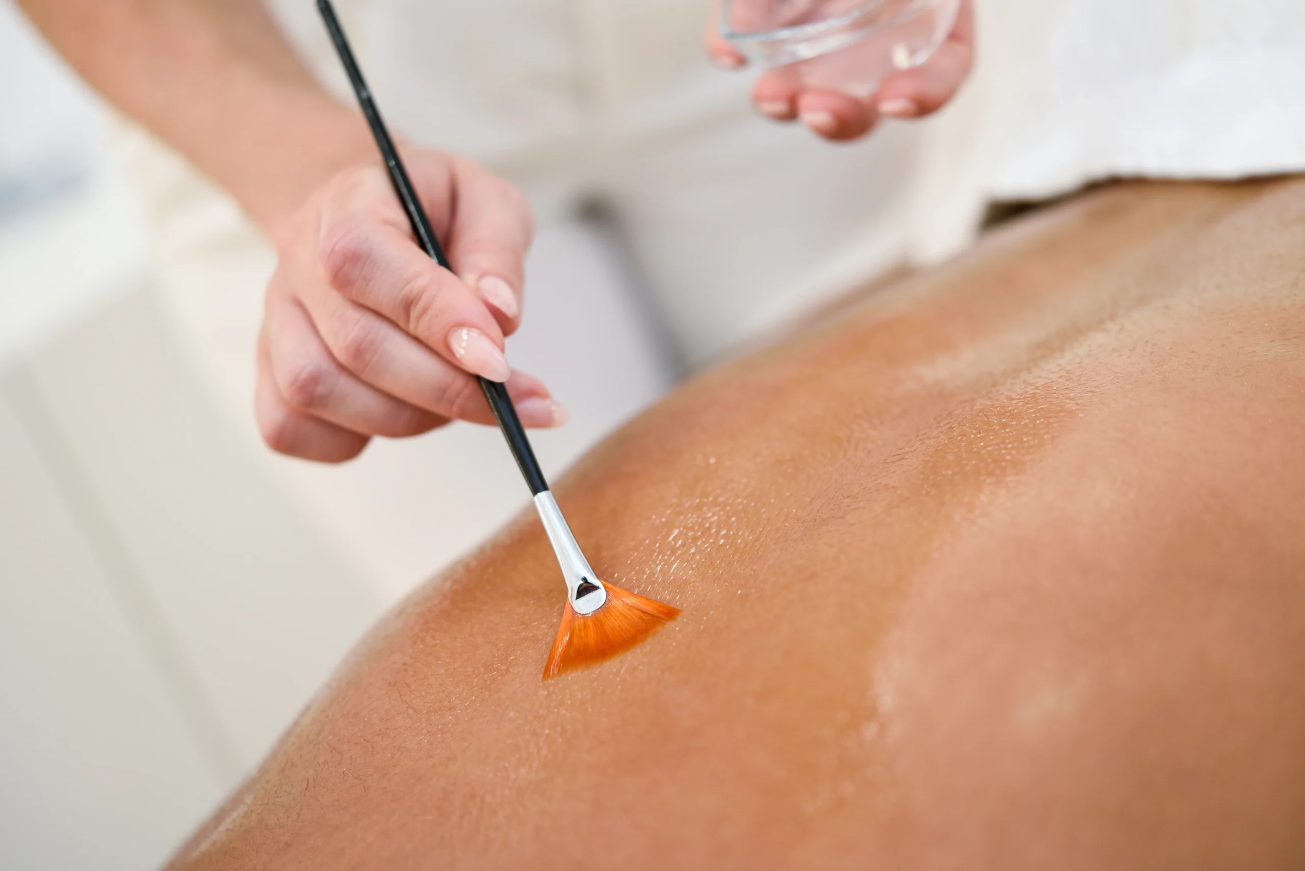 woman-receiving-back-massage-treatment-with-oil-brush